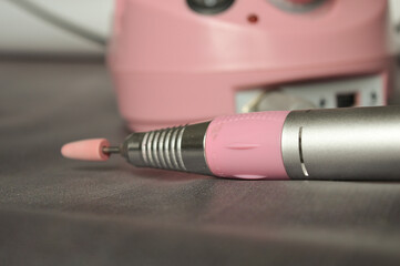 close-up of a hand holding an electric nail drill with ceramic bit. manicure tool used for nail...