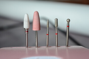 set of professional nail drill bits arranged vertically in a pink holder. different shapes and...