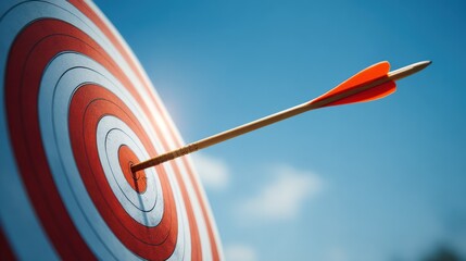 Close-up of a colorful archery target with an arrow hitting the bullseye against blue sky.
