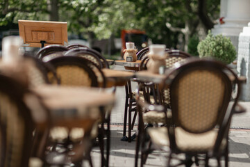 Cafe Chairs Tables: Sunny day, empty outdoor restaurant seats, tables in daylight await diners.
