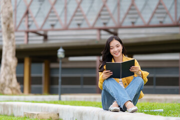 Smiling student reading a book on university campus