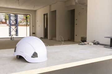 White hard Safety helmet on the window sill in a new house construction site. Protection equipment