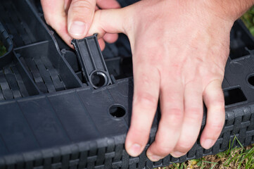 Assembling outdoor furniture: hands connecting plastic parts.