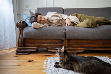 Depressed woman lying still in bed looking at cat for reassurance, mental fatigue and isolation....