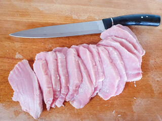 Raw pork meat cut into chunks on a wooden board. Pork meat cooking process. Preparing meat for chops or for meat in French