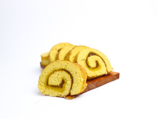 Close-up of sliced sponge cake roll with a swirl of jam filling, displayed on a wooden board