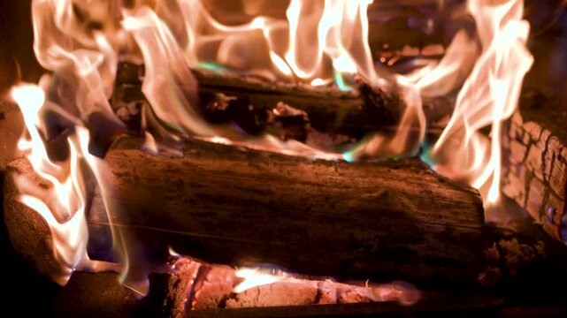 Burning fire logs inside stone fireplace. Christmas holidays at home. Burning fire warming up home. Cozy and warm living room. Close-up slow motion b-roll footage.