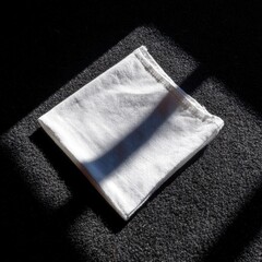 Folded white cloth on dark surface