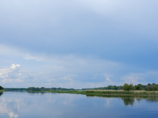 river and opposite bank with grass against blue sky
