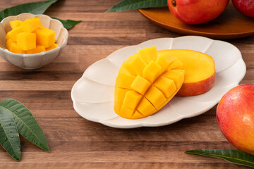Fresh ripe mango with cubes on wooden table background.