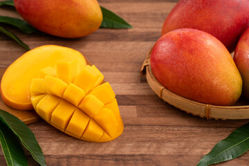 Fresh ripe mango with cubes on wooden table background.