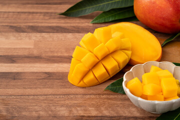 Fresh ripe mango with cubes on wooden table background.