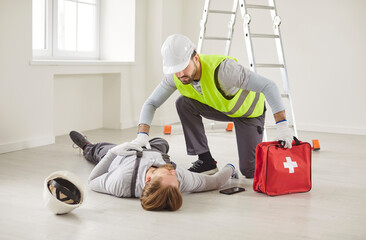 Injured unconscious young man worker handyman lying on the floor on building site with his worried...