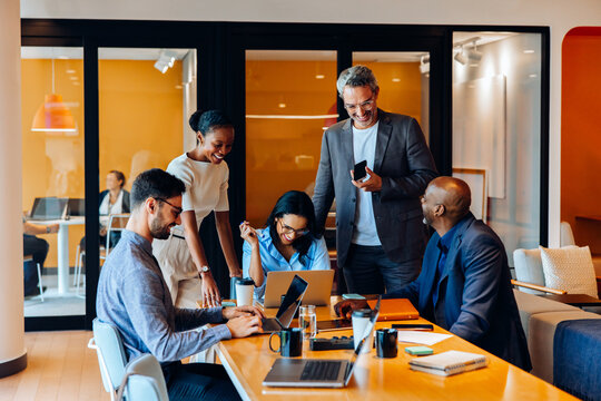 Fototapeta Group of professionals engaged in an active discussion in a bright office setting