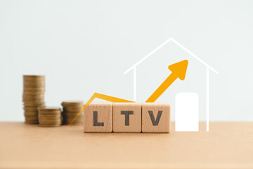 LTV, Loan to Value, text on wooden cube block with house icon and blurred stack of coins and increasing graph on blue background
