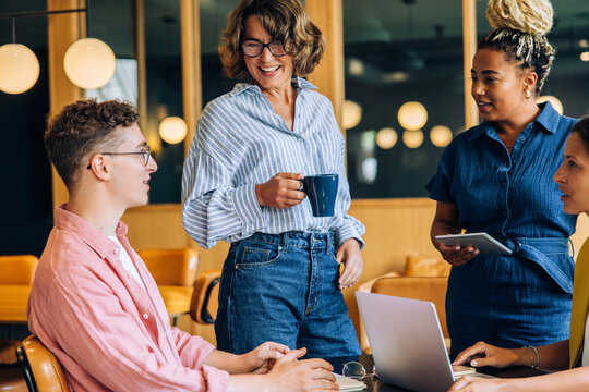 Diverse group in a modern office discussing work around a laptop setup