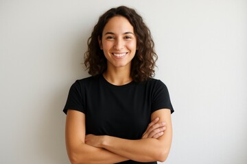 Obraz premium Portrait of smiling woman with curly hair standing with arms crossed against neutral background