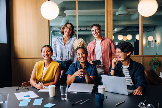 Group of young professionals laughing together at a meeting in an office