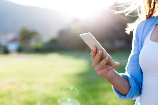 Woman using mobile phone outdoors. Technology lifestyle. Virtual connection, communication. Traveler walking, buying online with smartphone. Digital protection, cybersecurity. Close-up of female hand - Powered by Adobe