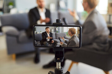 Smartphone screen showing blogger woman speaking using professional microphone, taking video for...