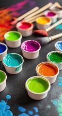 Colorful paint pots arranged on a dark surface