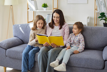 Family reading together at home, mother and small kids holding a book, enjoy warm and cozy shared...