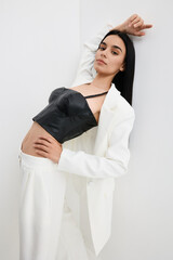 woman posing dressed in black leather top and white suit with stylish confident expression in...