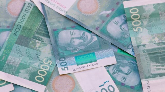 rotating background of 5000 Kyrgyzstani Som banknotes, closeup full-frame loopable background