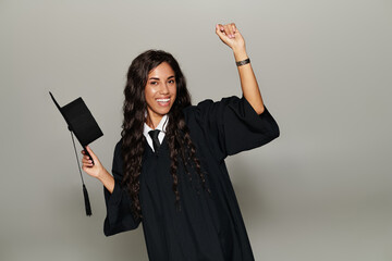 Celebratory student in a graduation gown expressing joy and pride at a milestone achievement