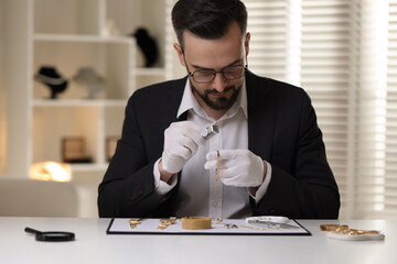 Appraiser with loupe evaluating luxury bracelet at table indoors