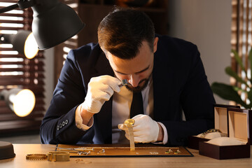 Appraiser with loupe evaluating luxury wristwatch at table indoors