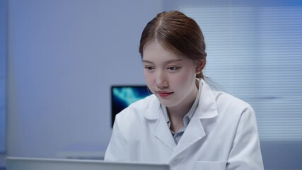 Professional female scientist analyzing medical data on laptop while working in modern laboratory with advanced monitoring equipment in background - Powered by Adobe