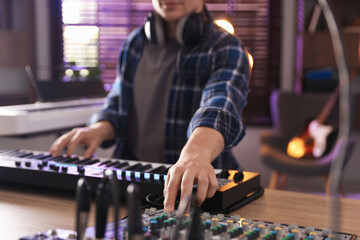 Man working with MIDI keyboard and dj mixer at table, selective focus