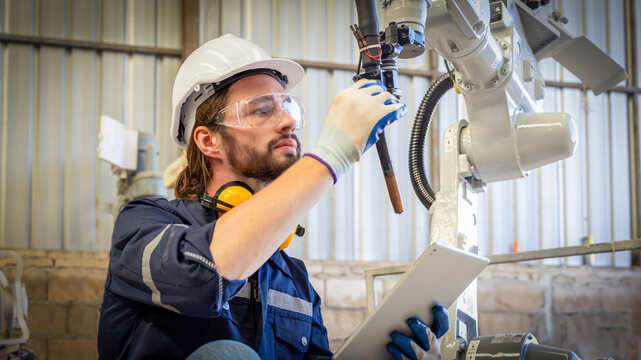 Electrical engineer testing artificial intelligence robot arm at high technology research manufactue with equipment. Factory workers working with adept robotic arm.