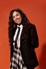 Smiling student radiates youthful energy in uniform against tangerine backdrop