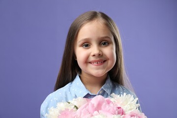 Cute little girl with bouquet of beautiful peonies on purple background