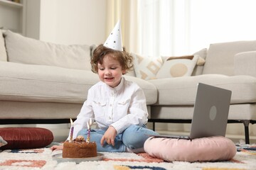 Birthday celebration. Little boy with cake having video call via laptop at home