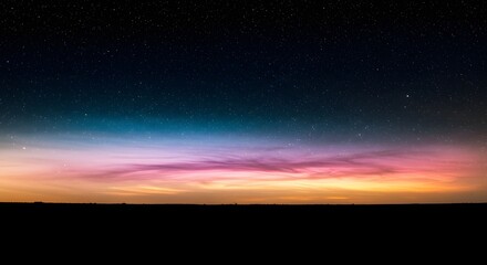 A vibrant aurora borealis paints the night sky with colorful hues above a dark silhouette of land, creating a dreamy and peaceful landscape