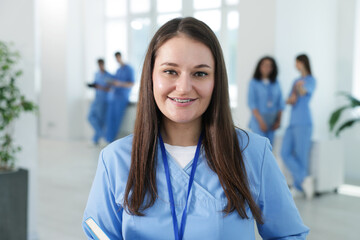 Medical student in uniform with notebook indoors, selective focus