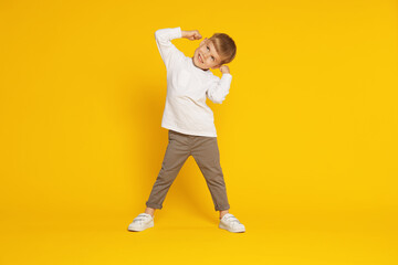 Happy little boy dancing on orange background