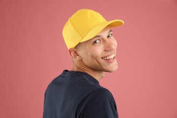 Young man in stylish baseball hat on pink background