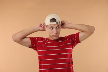 Naklejka premium Young man in stylish baseball hat on beige background