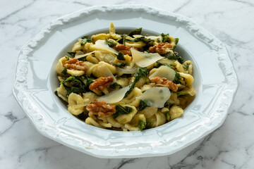 Orecchiette pasta with radish greens, walnuts, and parmesan, seasoned with nutmeg. Italian cuisine. 