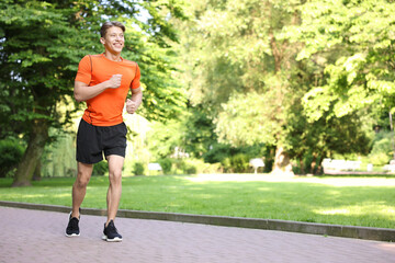 Sporty man running in park, space for text