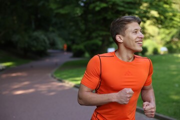 Sporty man running in park, space for text