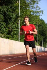Sporty man with headphones running at stadium