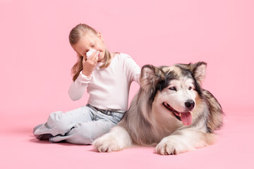 Girl suffering from allergy with her dog on pink background