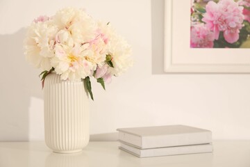 Bouquet of beautiful peonies and books on table indoors