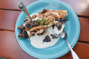 A blue plate topped with chicken and mushrooms, served with a spoon