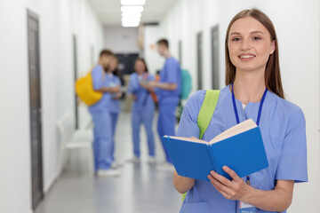 Medical student in uniform with backpack and notebook indoors, selective focus